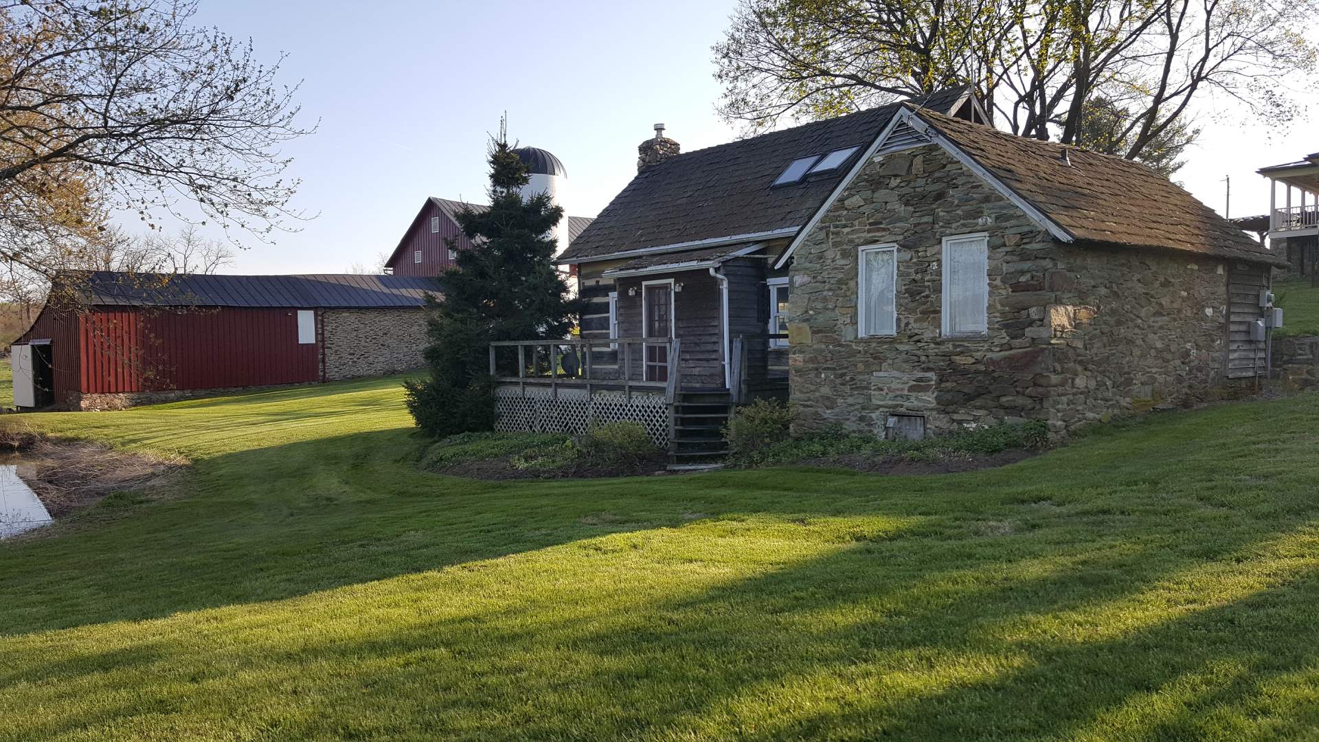 A small stone cottage sits next to a pond.