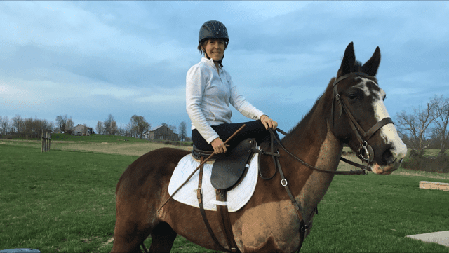 A woman riding a brown horse in a field.