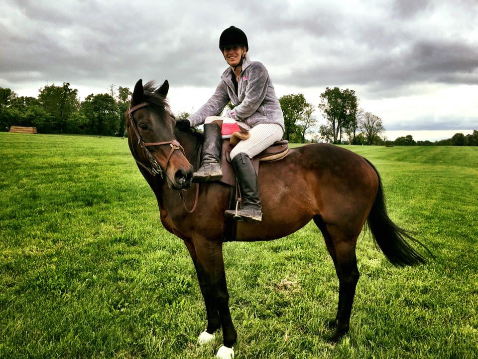 A woman riding a brown horse in a field.