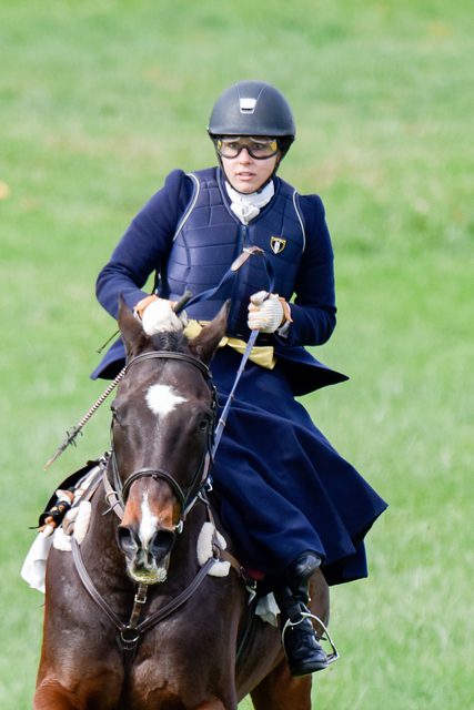 Lady riding a running horse in an open field