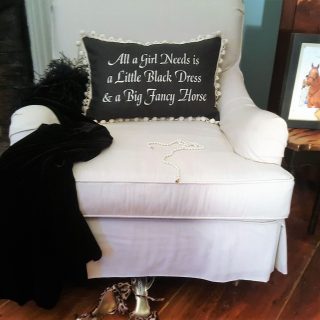 A pillow in black kept on a white chair