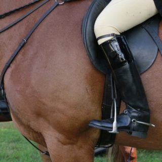 Close up shot of a man putting his leg on a horse