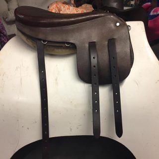 A brown saddle with straps on top of it.