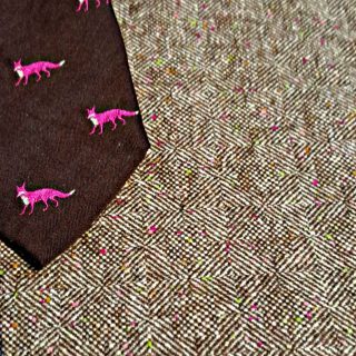 A brown tie with pink foxes on it.