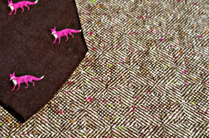 A brown tie with pink foxes on it.