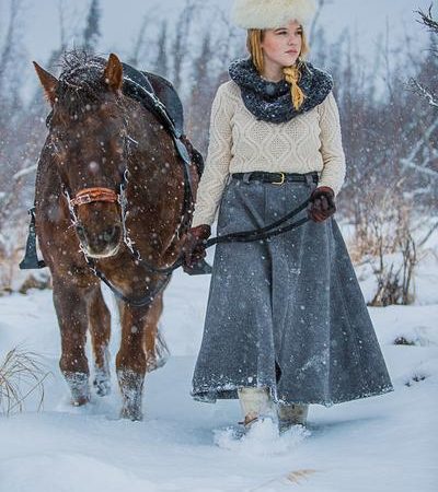 A small girl in snow with a horse